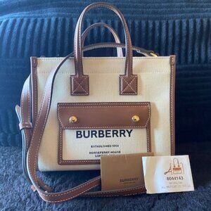 A compact Burberry tote made in Italy. cotton canvas trimmed with leather.